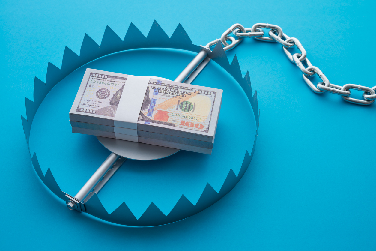 Pile of money dollar banknotes in trap on blue background.