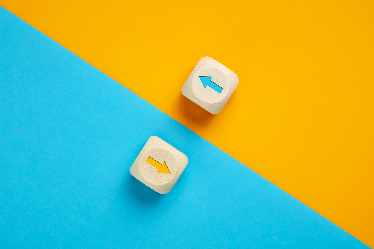 Arrow icons in contrast on wooden cubes moving towards opposite directions. Competition, diversity, opposition or confrontation concept.